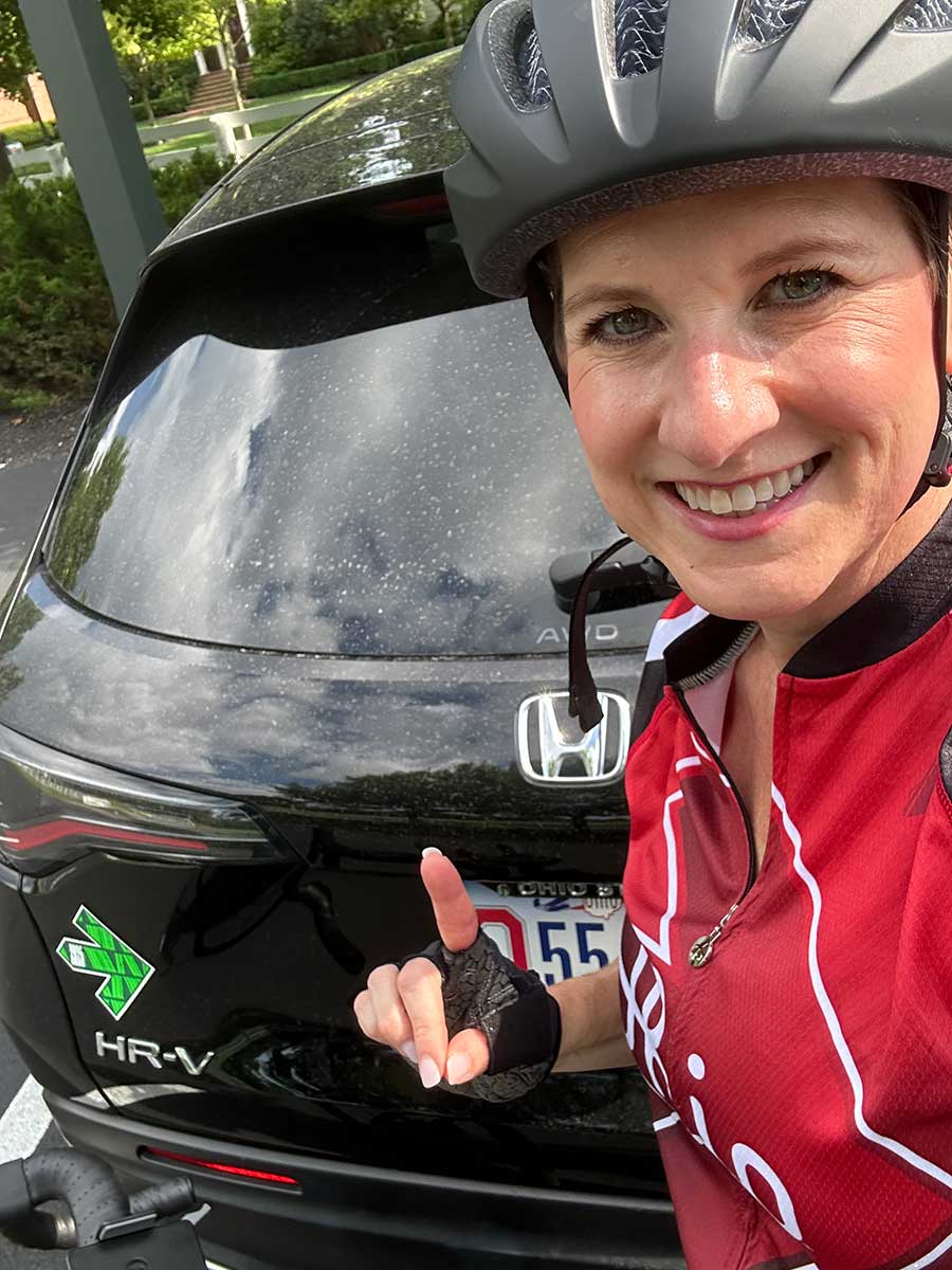 Julie Kriss on her bike next to the car with the Pelotonia sticker on it