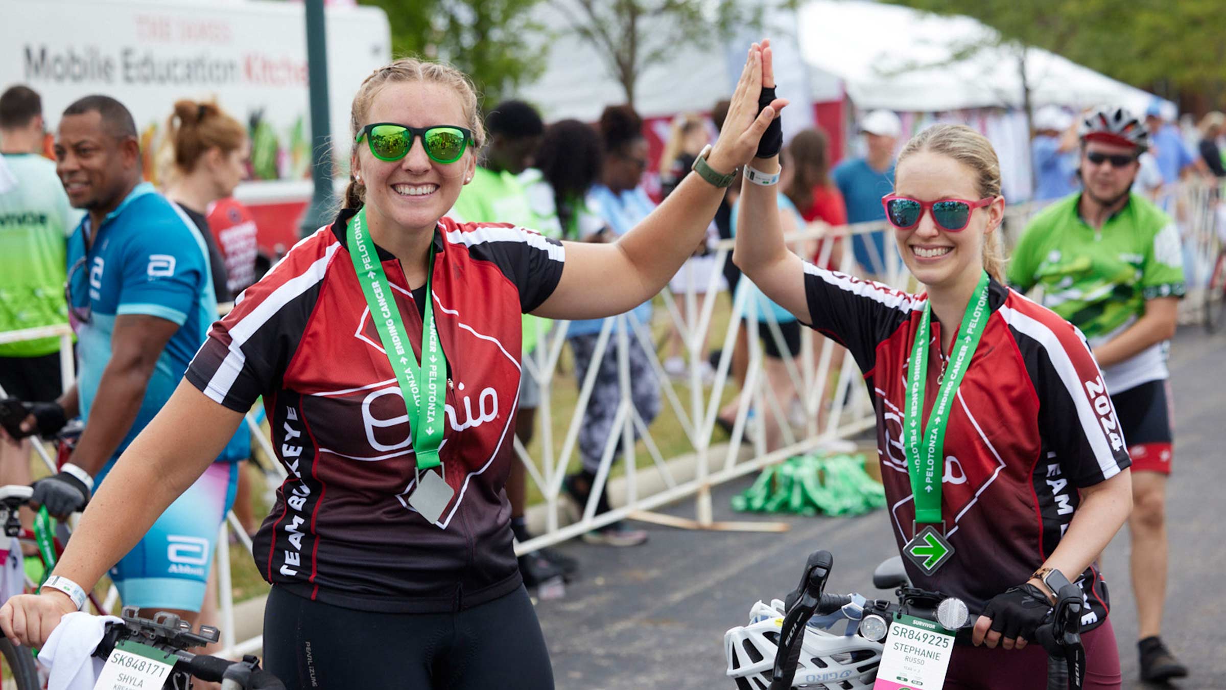 Two Pelotonia riders high-five, medals hanging around their necks