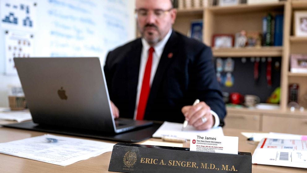 Dr. Singer sitting at a desk in front of a laptop