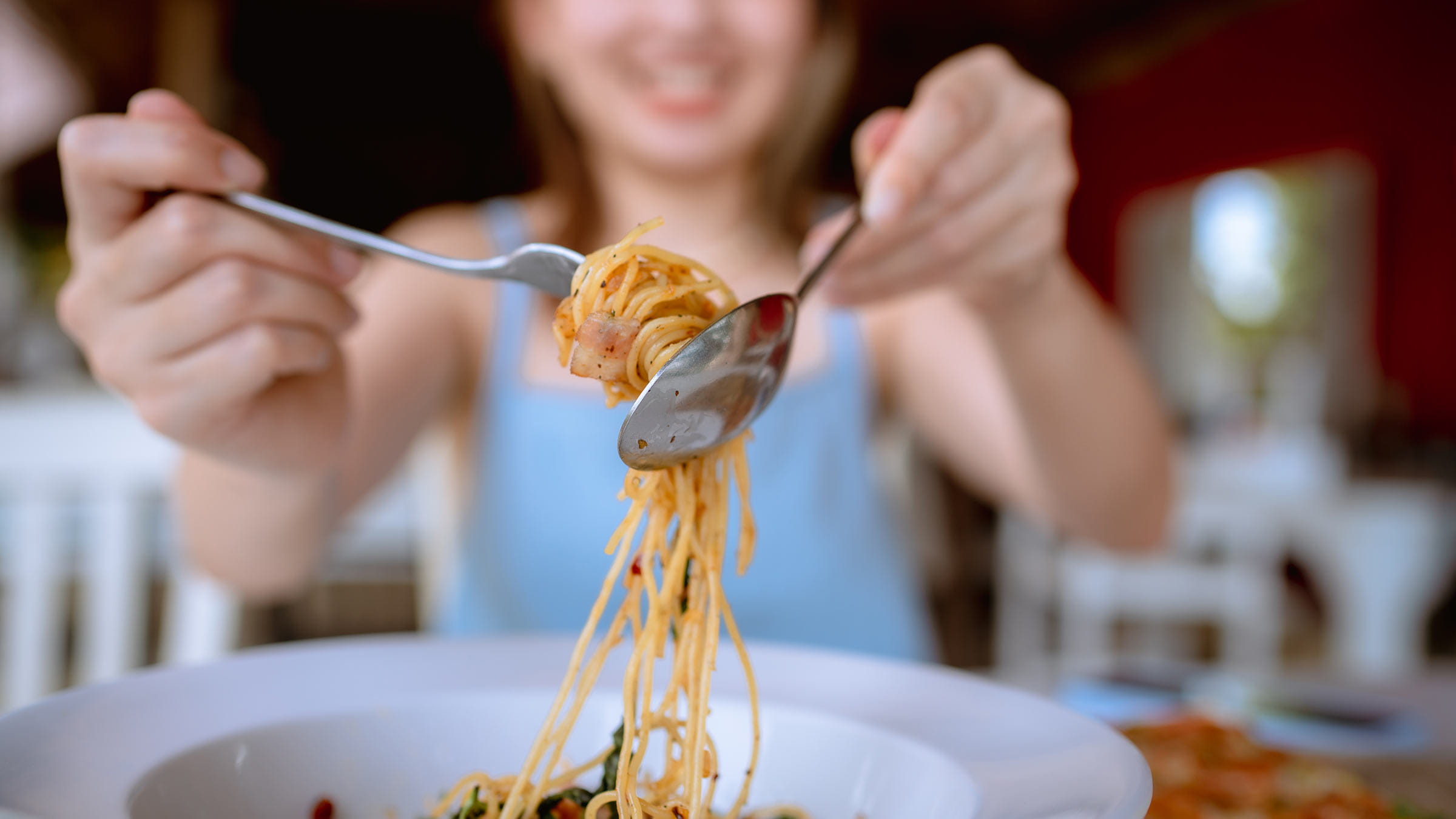 A woman twirling pasta on a fork
