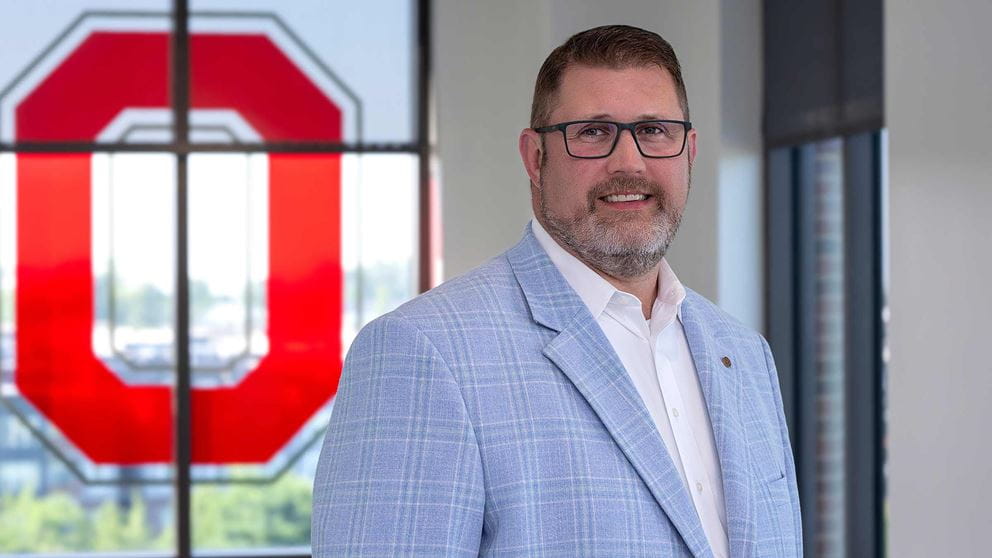 Doctor Matthew Beal standing in front of the stained glass “Block O”