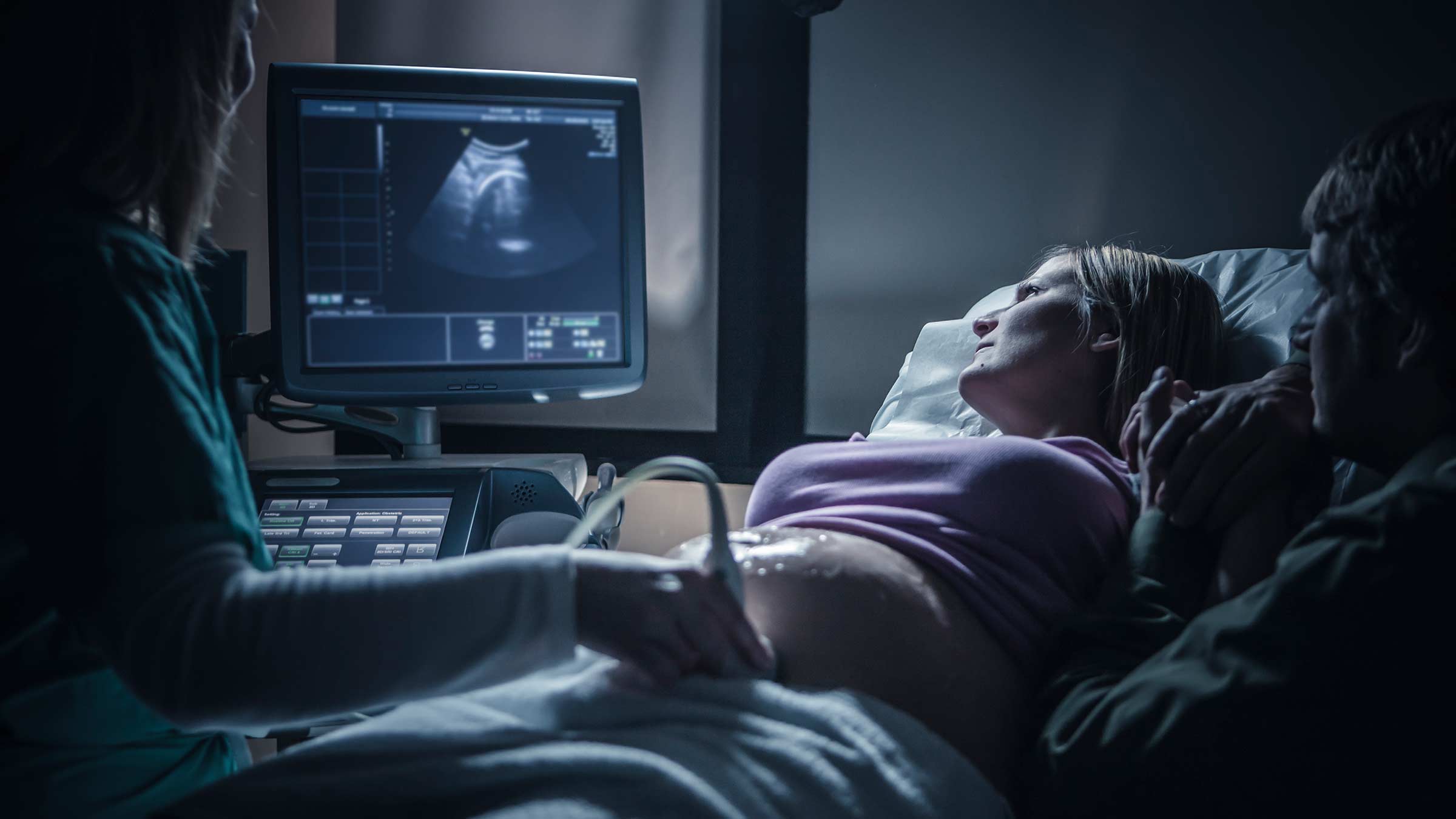 A pregnant woman looking at the ultrasound monitor during her scan