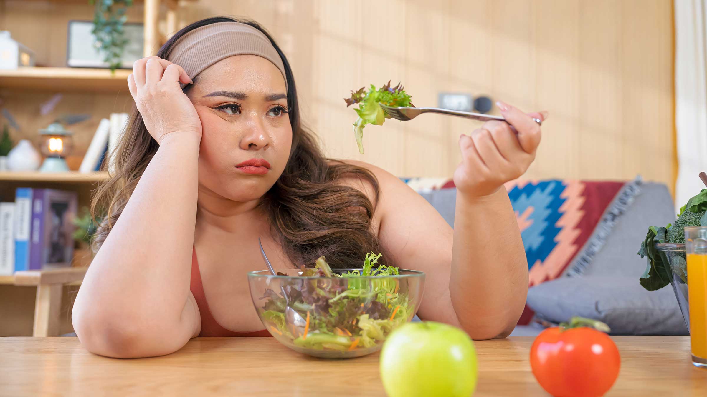 A woman staring sadly at a bowl of plain lettuce