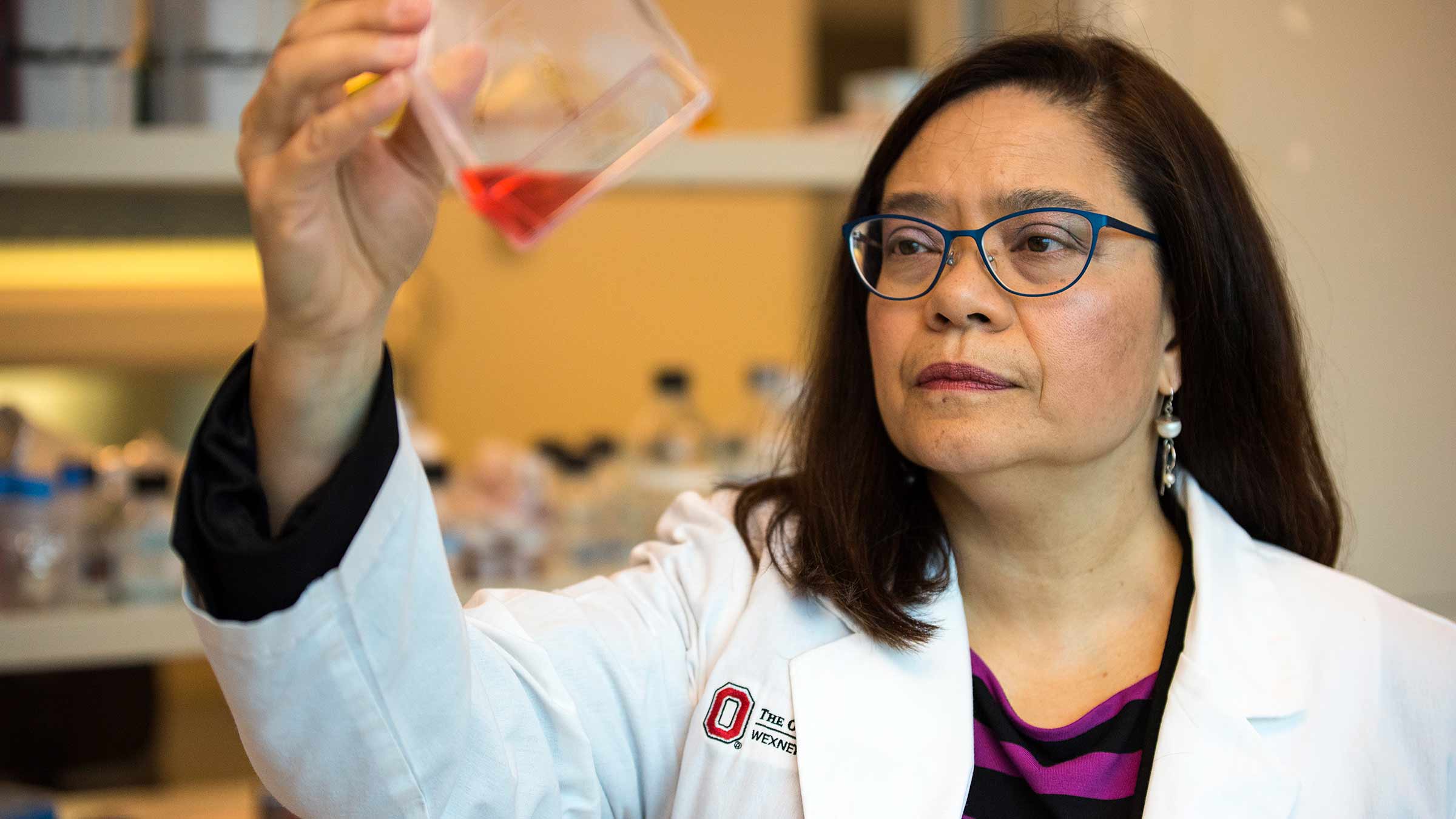Dr. Ginny Bumgardner looking at a container filled with red liquid