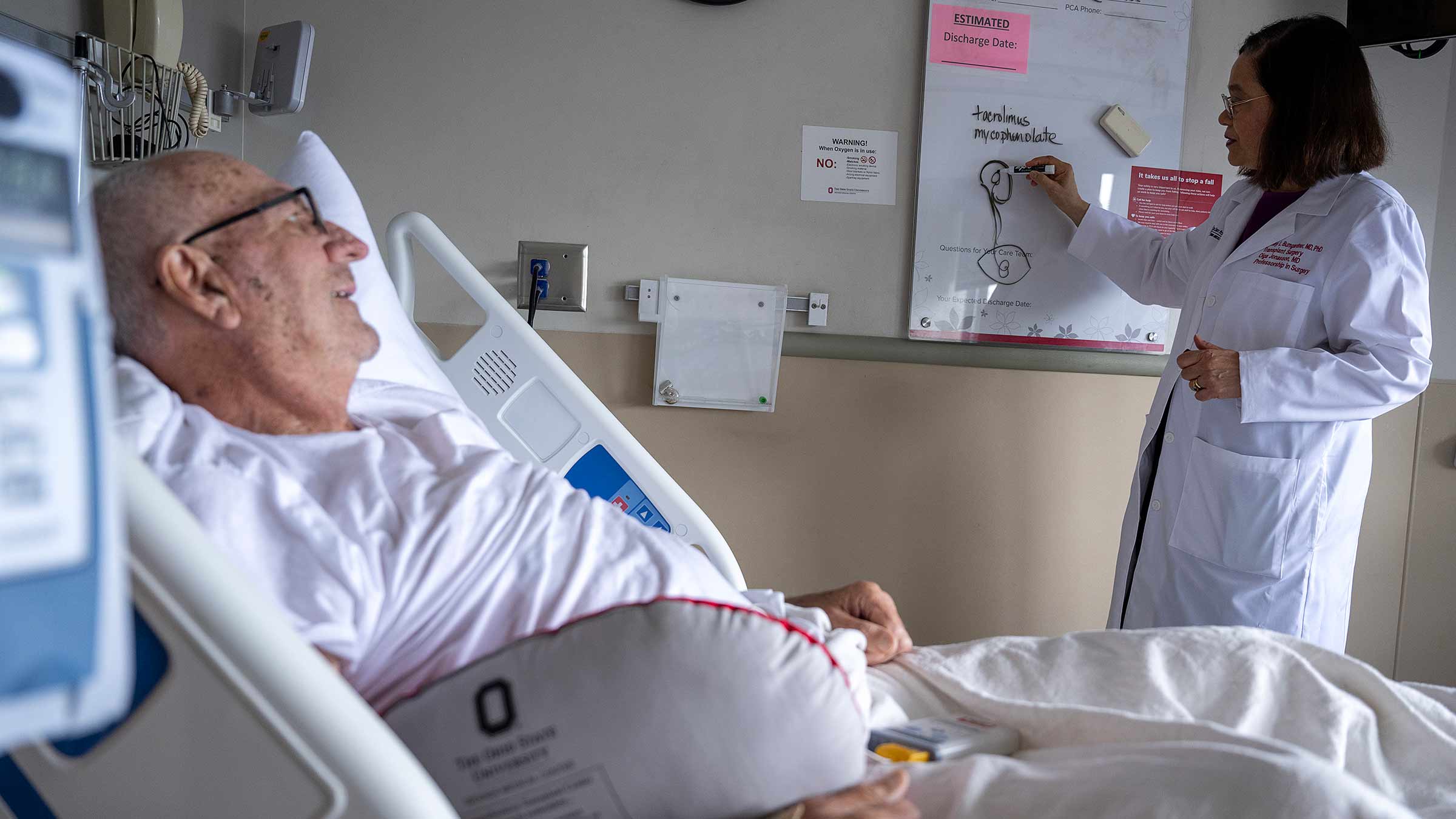 Dr. Ginny Bumgardner draws on a whiteboard while talking to organ transplant patient, James Green