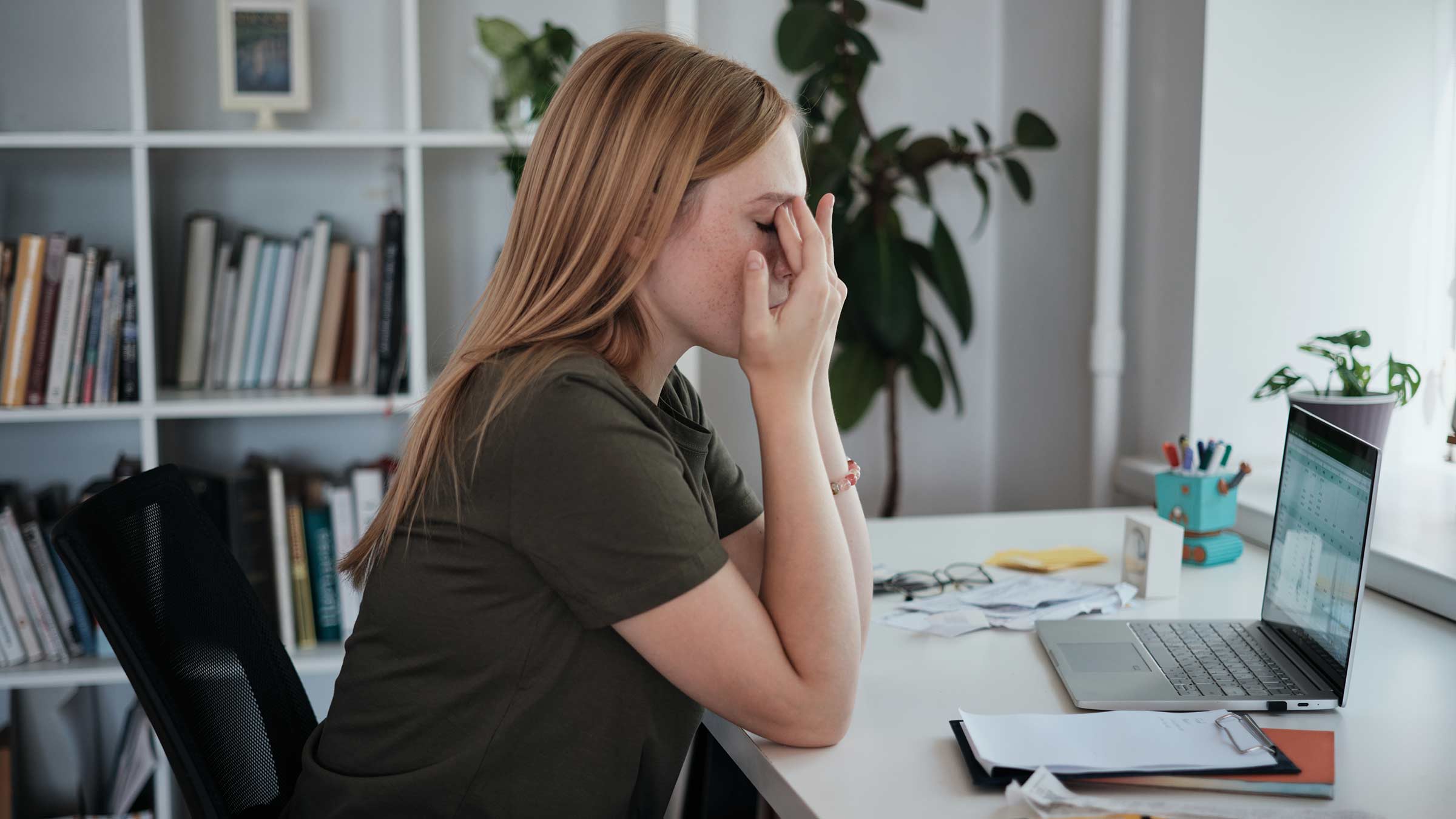 Woman sitting in front of a computer rubbing her eyes