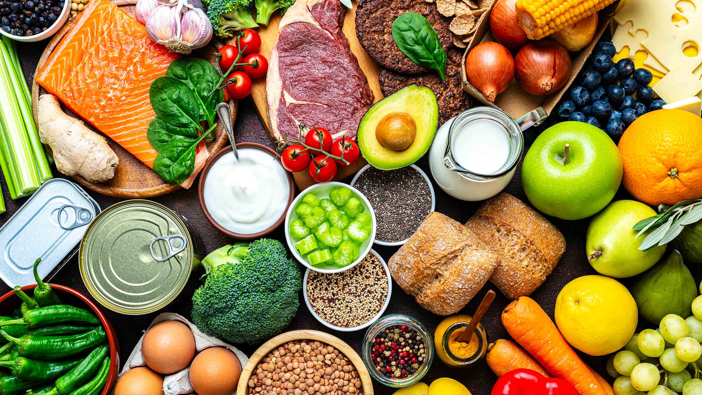 A variety of healthy food on a table including eggs, broccoli, salmon and avocado