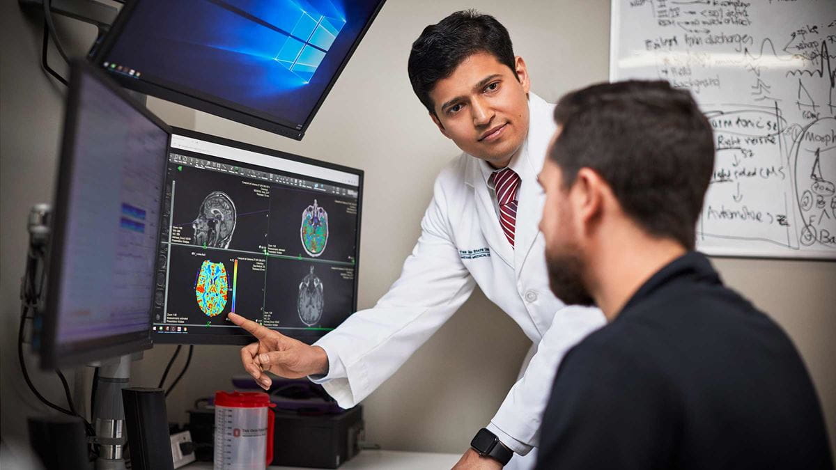 Dr. Jaysingh Singh pointing to a brain scan on a computer screen