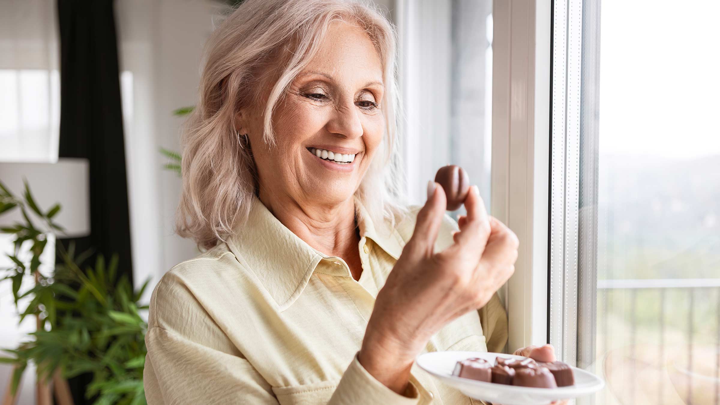 An older woman eating a piece of chocolate