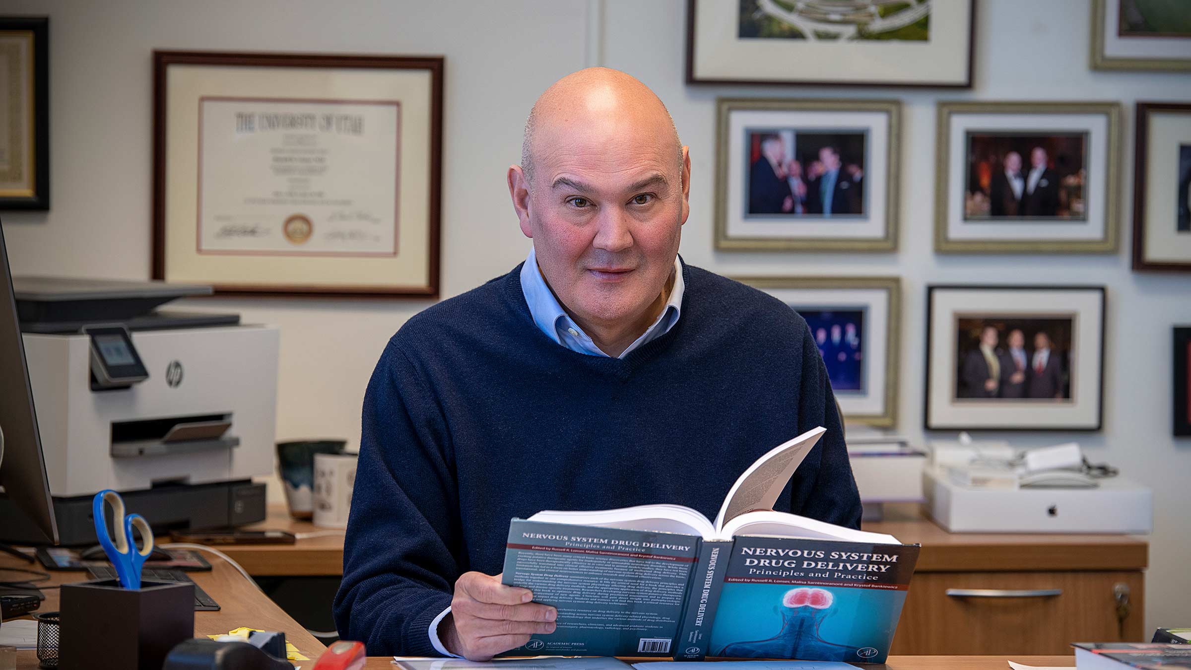 Dr. Lonser at his desk with a book in his hands