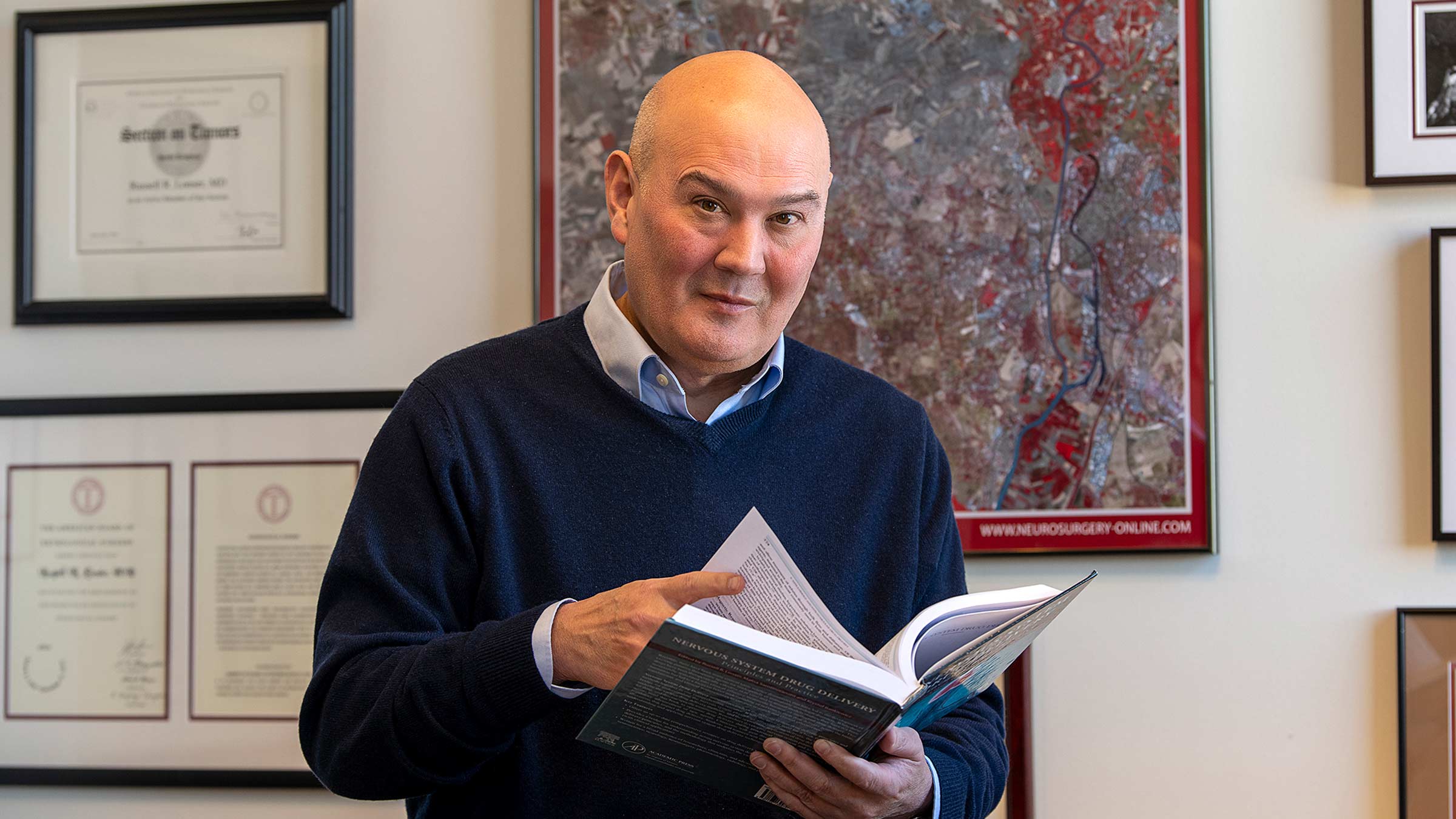 Dr. Lonser in his office holding a book