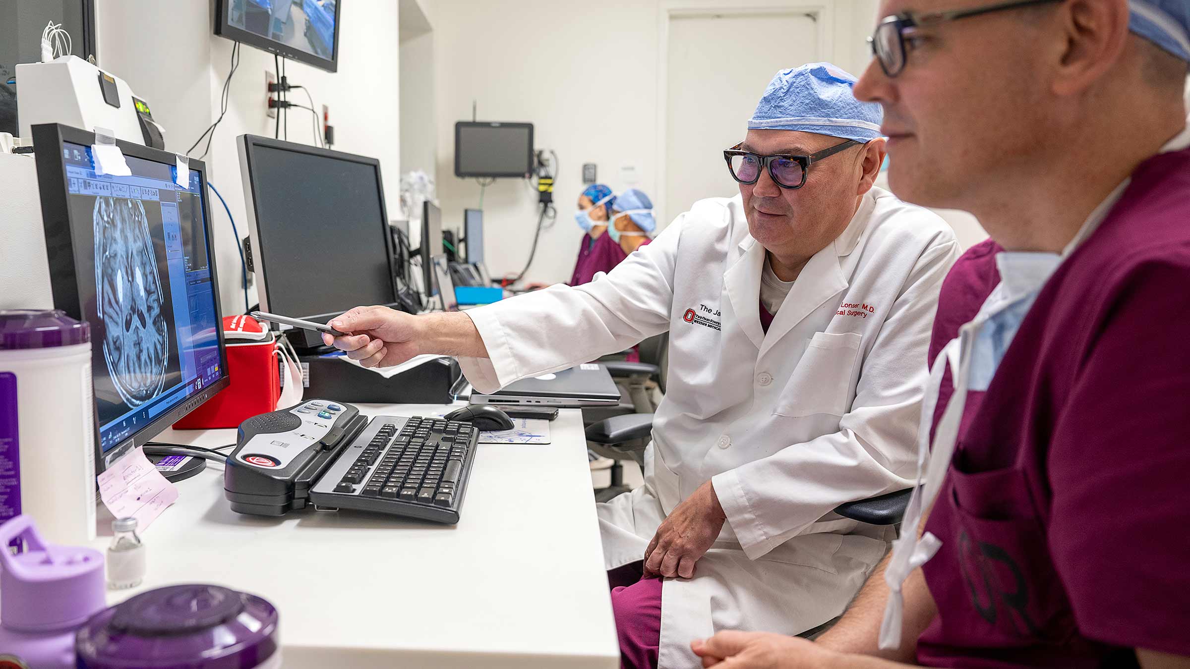 Dr. Lonser talking to Dr. Elder and pointing to a computer screen