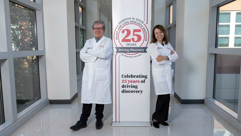 Dr. Mora and Dr. Rojas standing next to the sign: "Dorothy M. Davis Heart and Lung Research Institute: Celebrating 25 years of driving discovery"