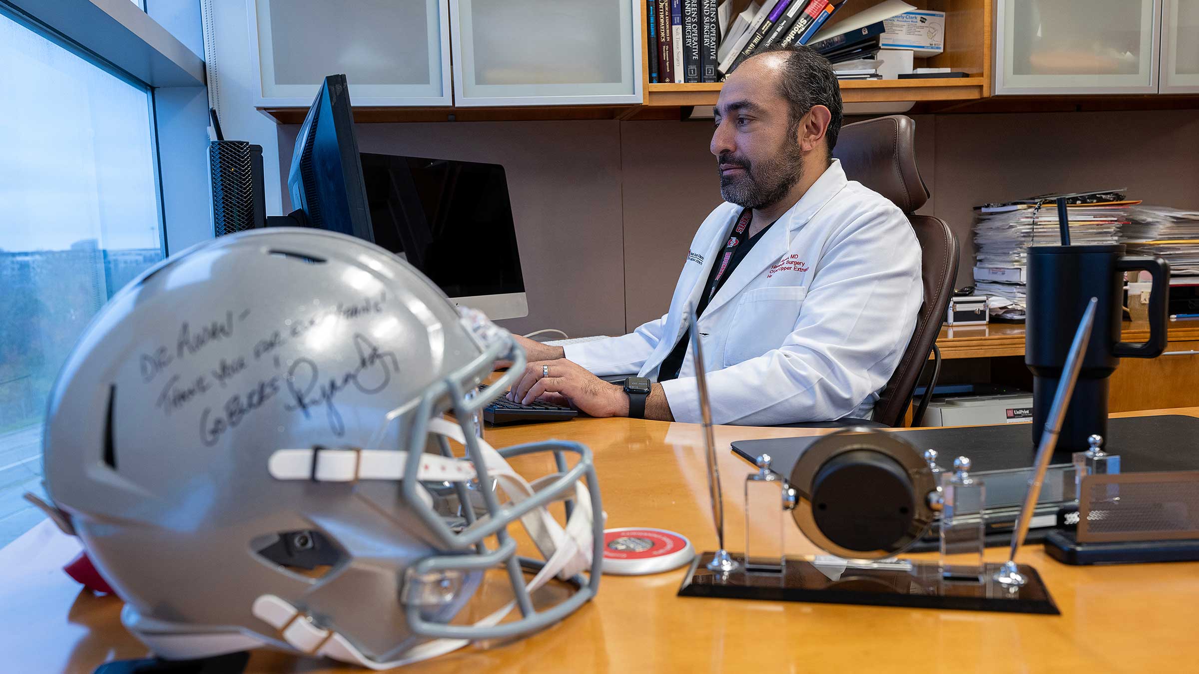 Dr. Awan in his office, with a signed football helmet on his desk