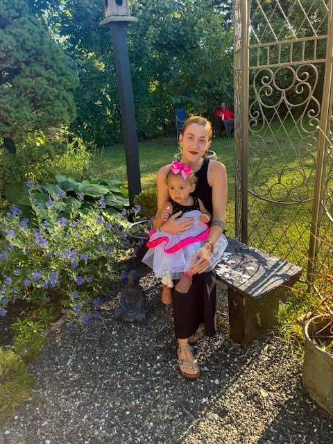 Chloe Lengle sits with her daughter on a bench in a garden
