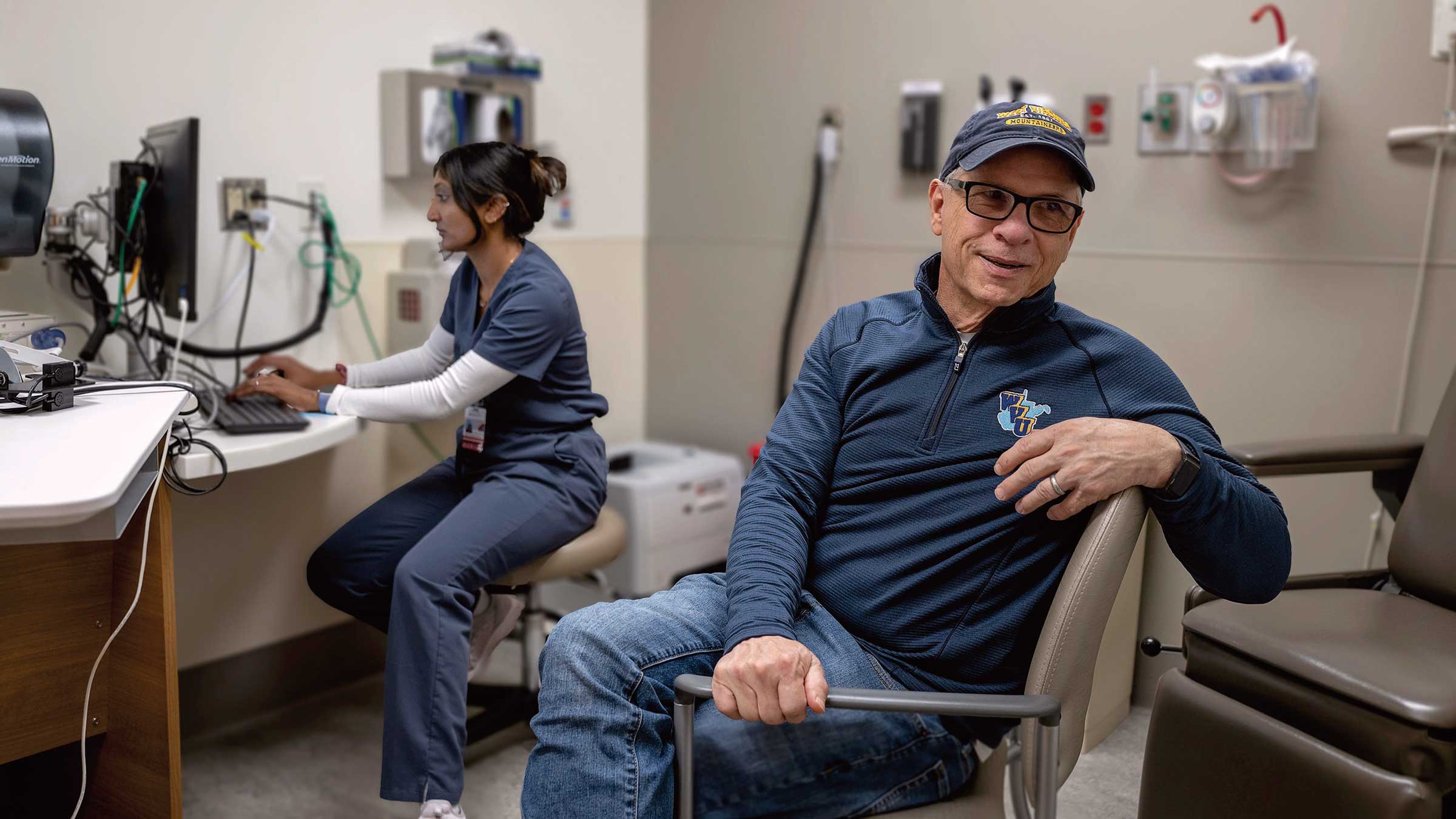 Randall Wright, wearing a WVU shirt, leans back in his chair in an Ohio State clinic