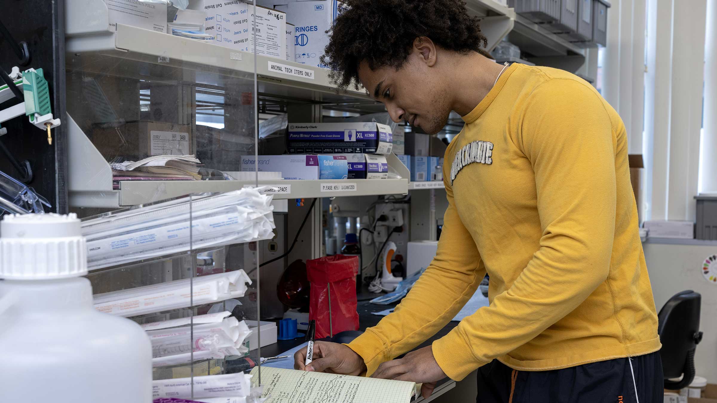 A lab worker writing notes in a notebook