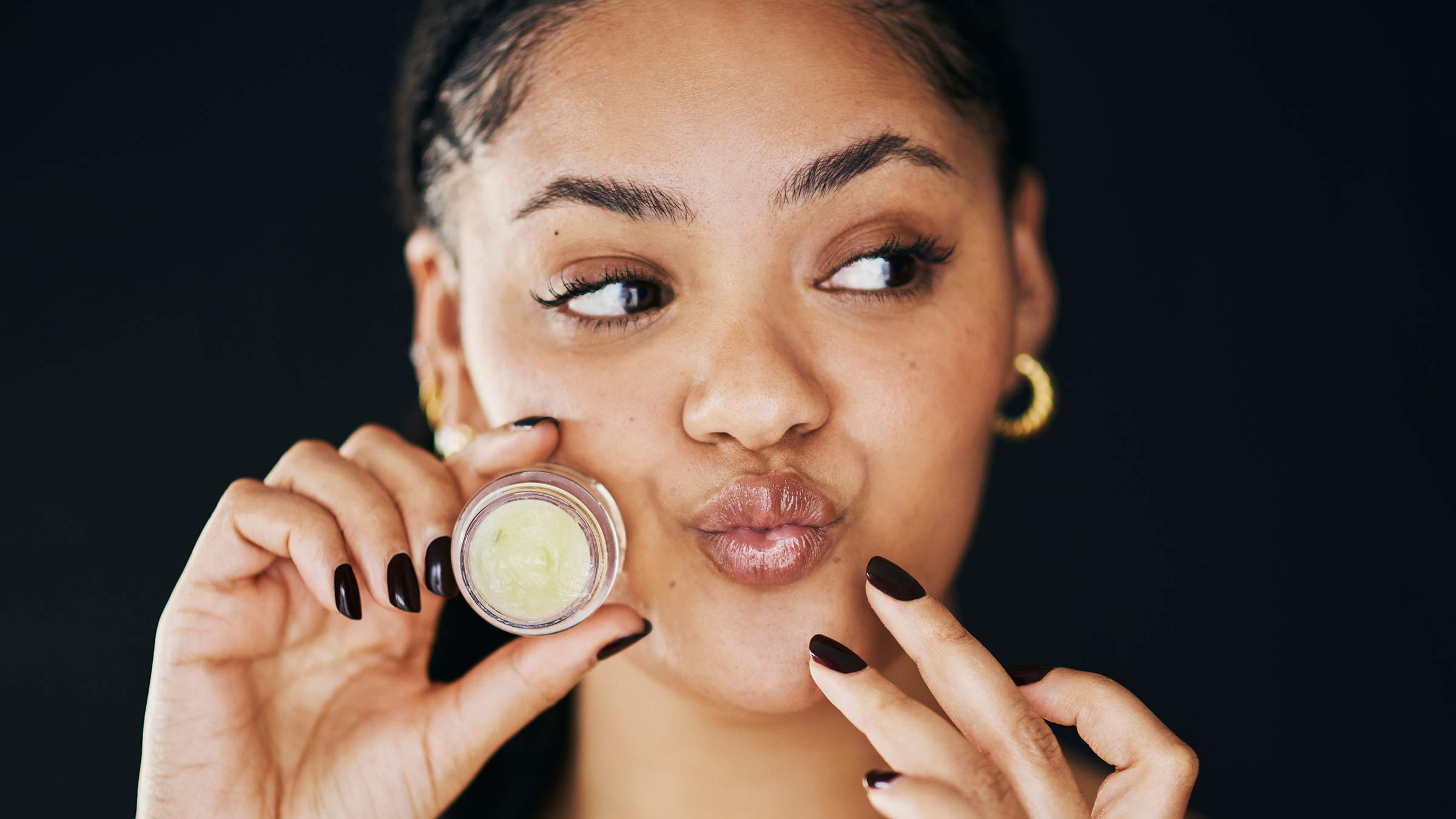 A woman applying lip balm to her lips