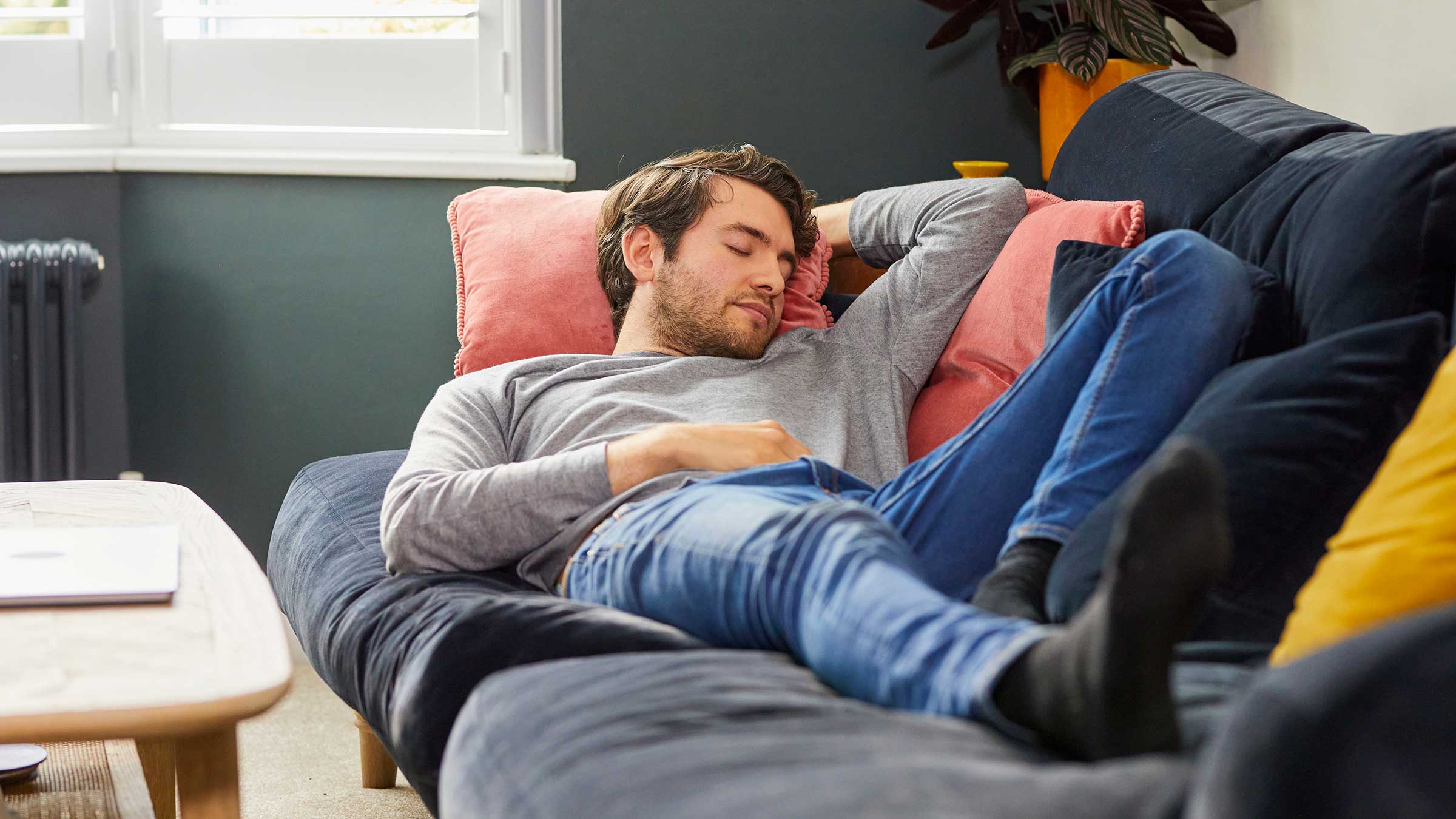 A young man takes a nap on a navy couch