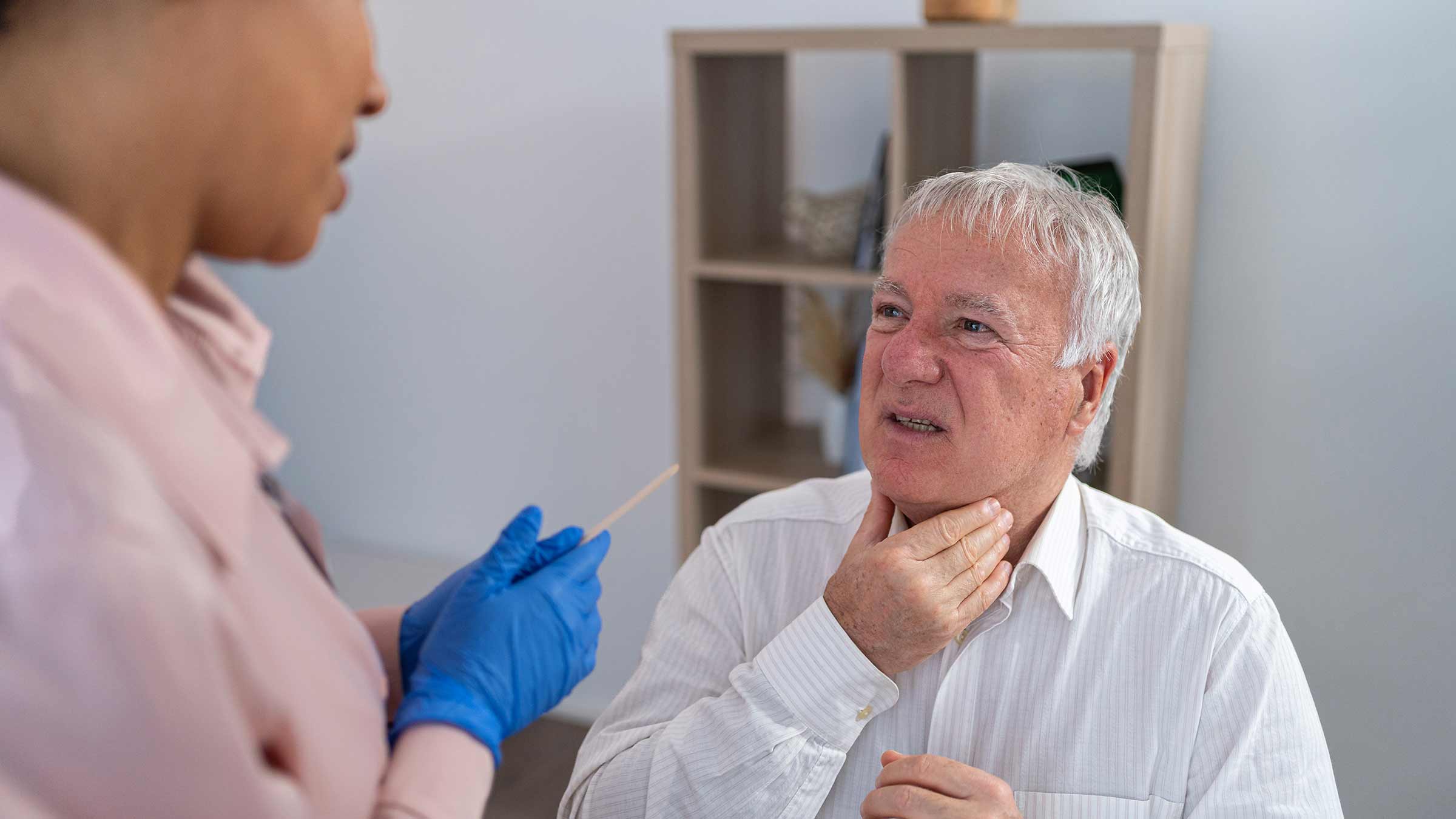 A man talking with a doctor and pointing to his throat