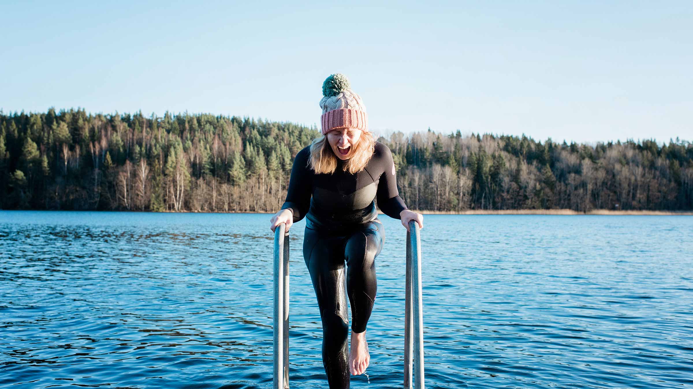 A woman coming out of a lake after a cold plunge
