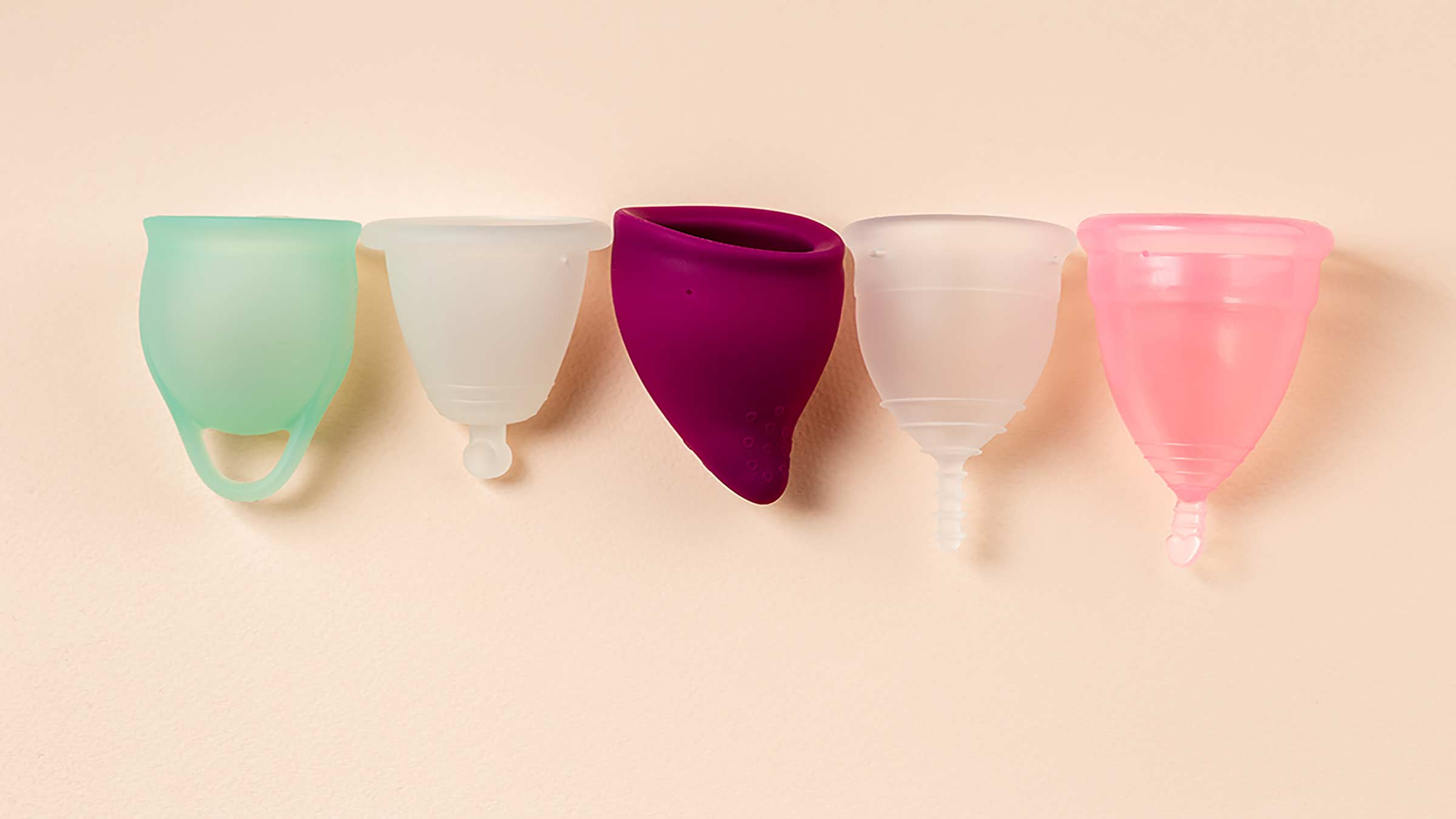 Different types of menstrual cups on a pink background