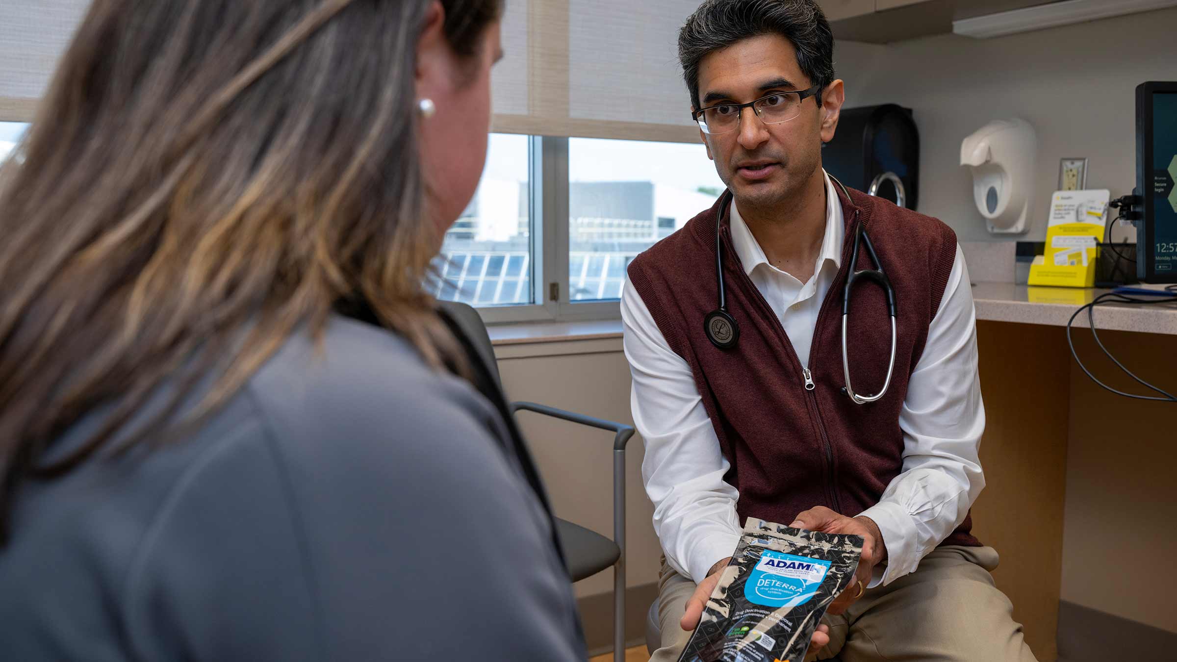 Dr. Sachin Kale shows a patient an alternative product for pain management during thier cancer treatment