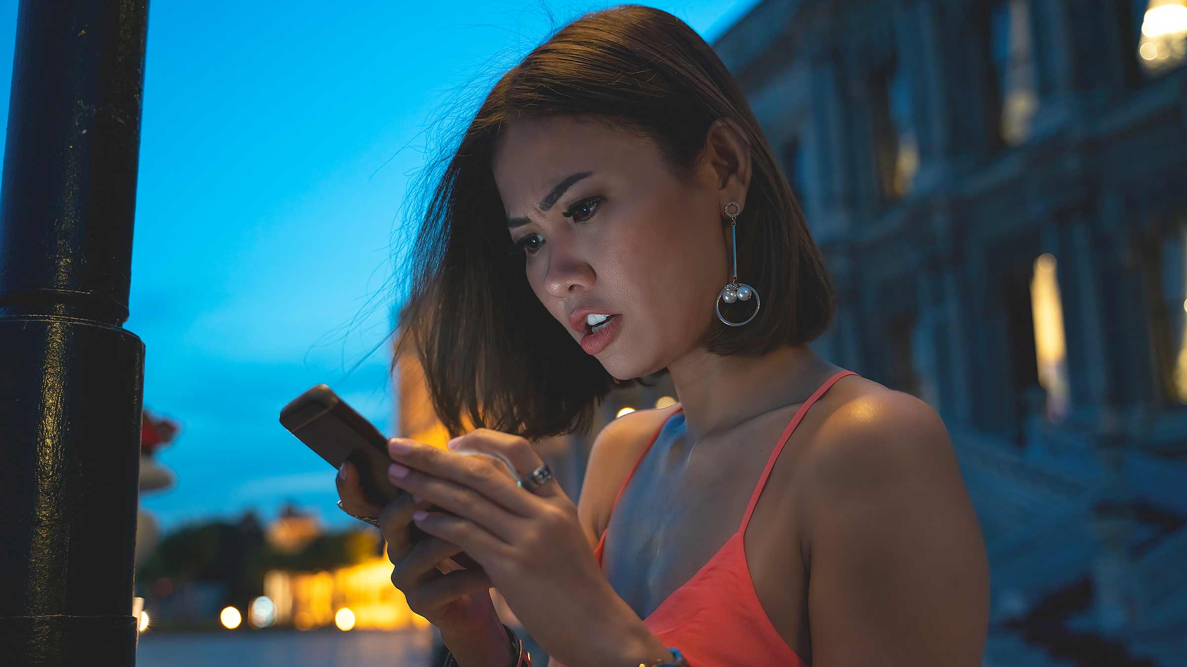 A young women looking down at her cell phone with an upset expression