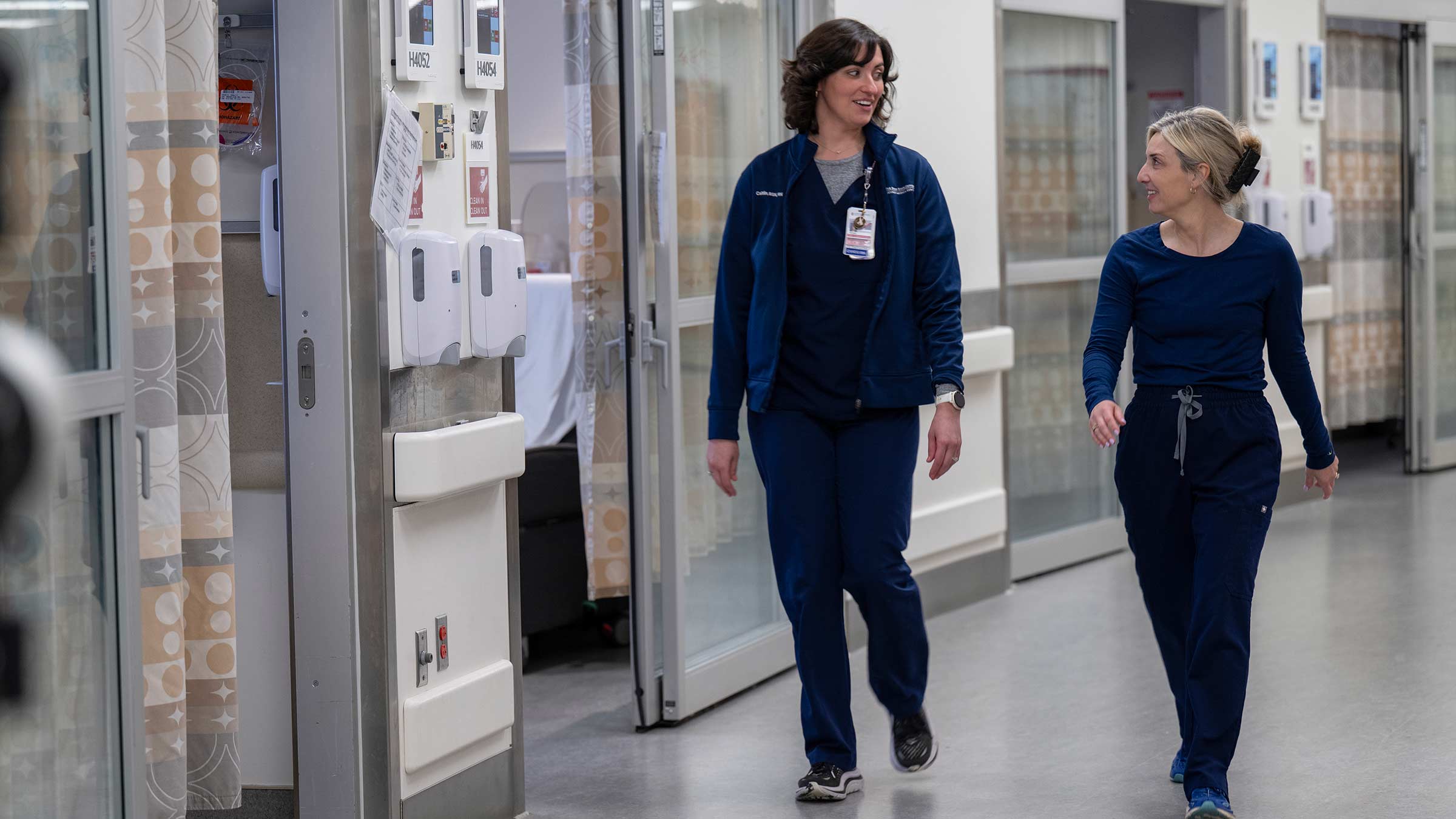Caitlin Conner walking down the hall in her nurse uniform alongside another nurse