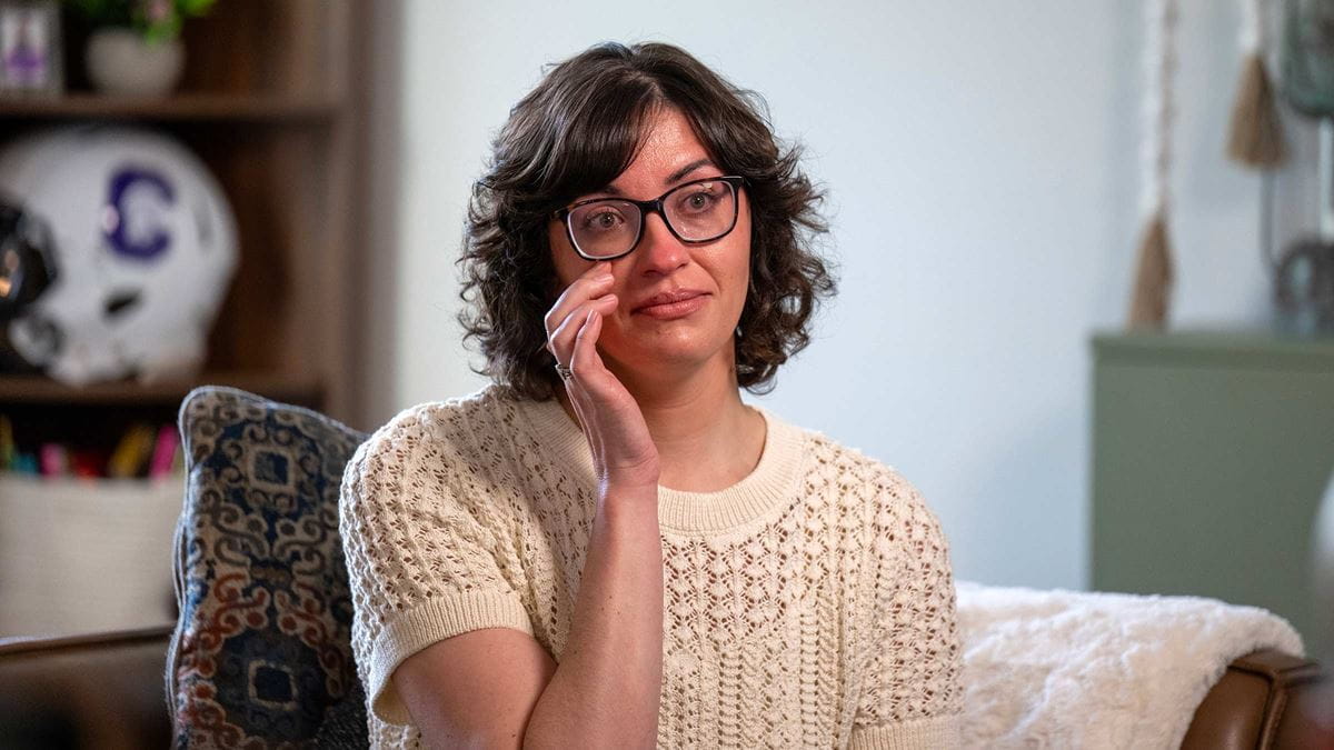 Breast cancer survivor, Caitlin Conner, wiping a tear
