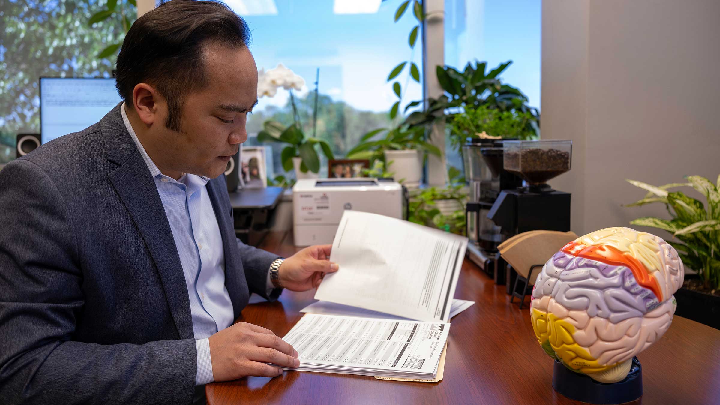 Christopher Nguyen, PhD, ABPP, reviewing data at his desk 