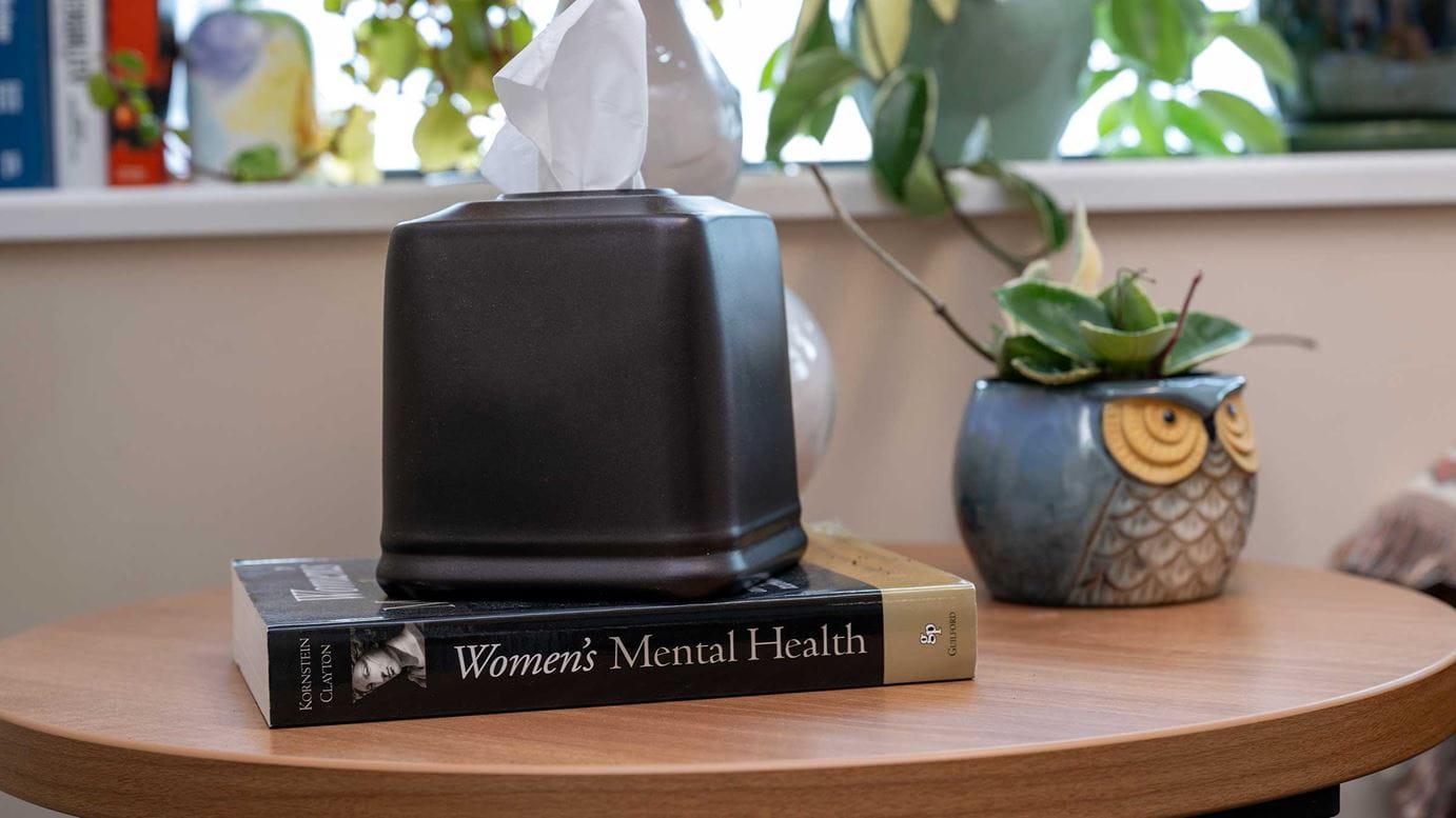 "Women's Mental Health" book laying on the table with a box of tissues on it