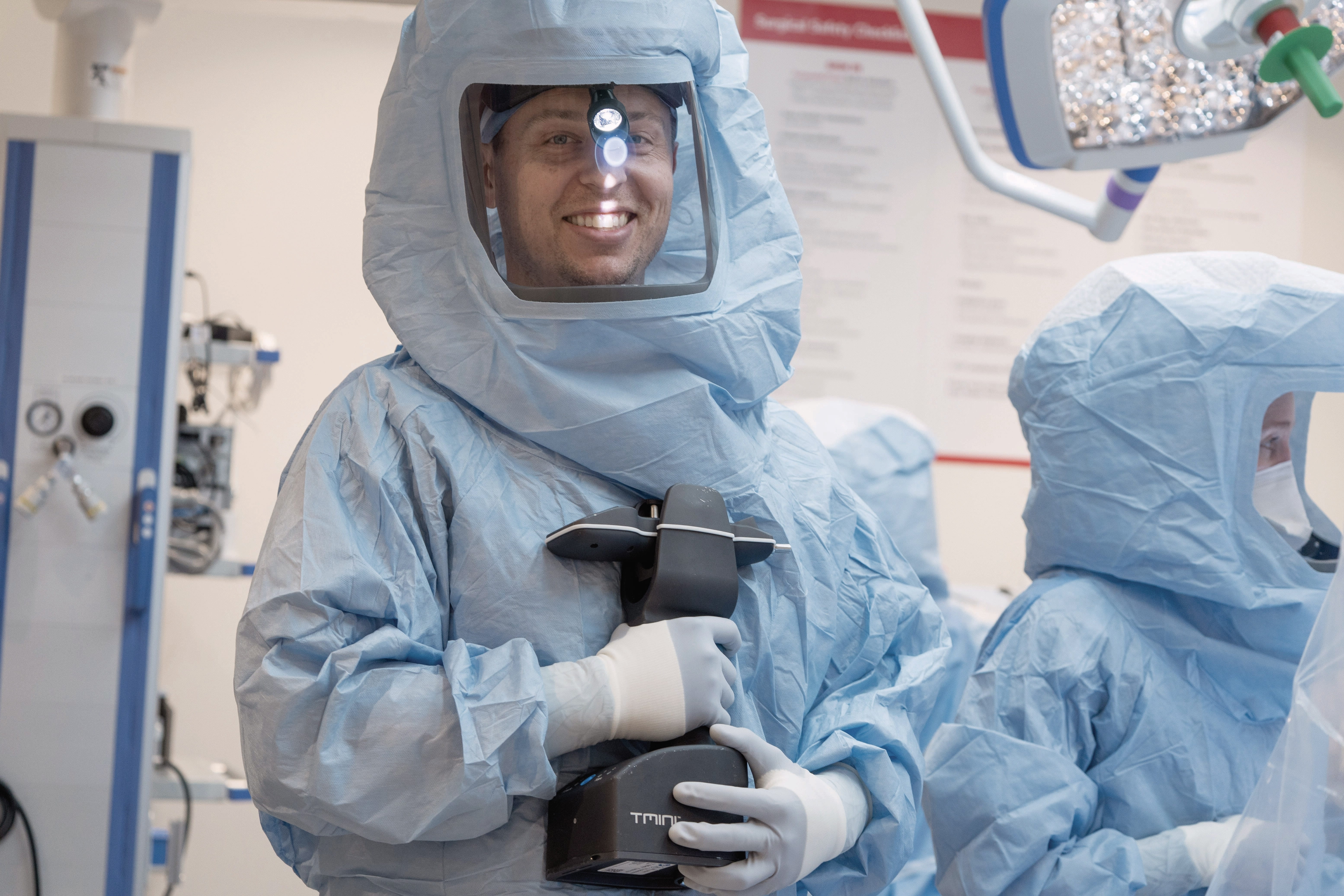 Dr. Reeves suited up in the OR with the handheld robotic machine for joint replacements