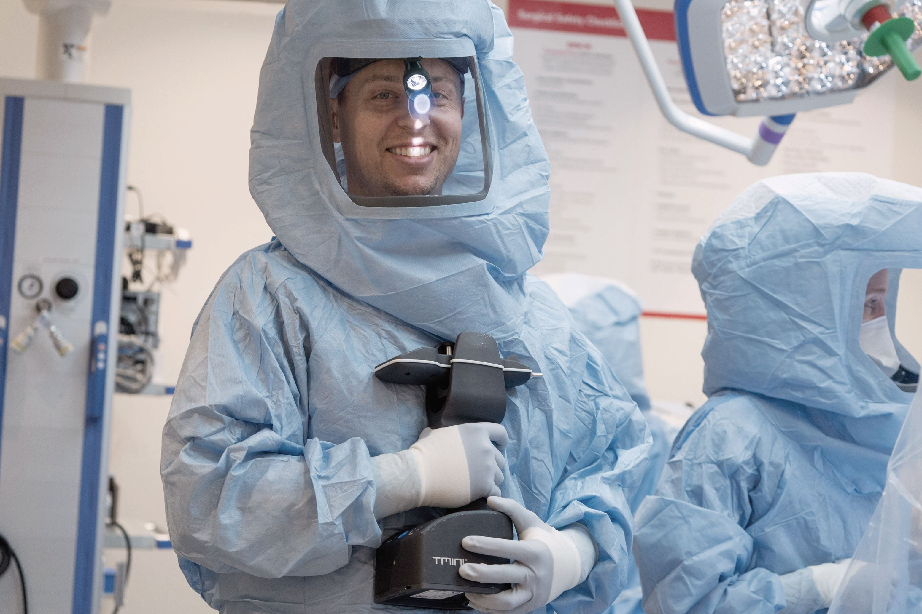 Dr. Reeves suited up in the OR with the handheld robotic machine for joint replacements