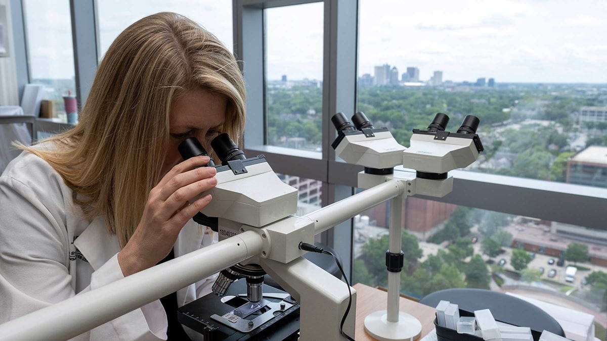 Dr. Alice Mims examining a sample with a telescope in the lab
