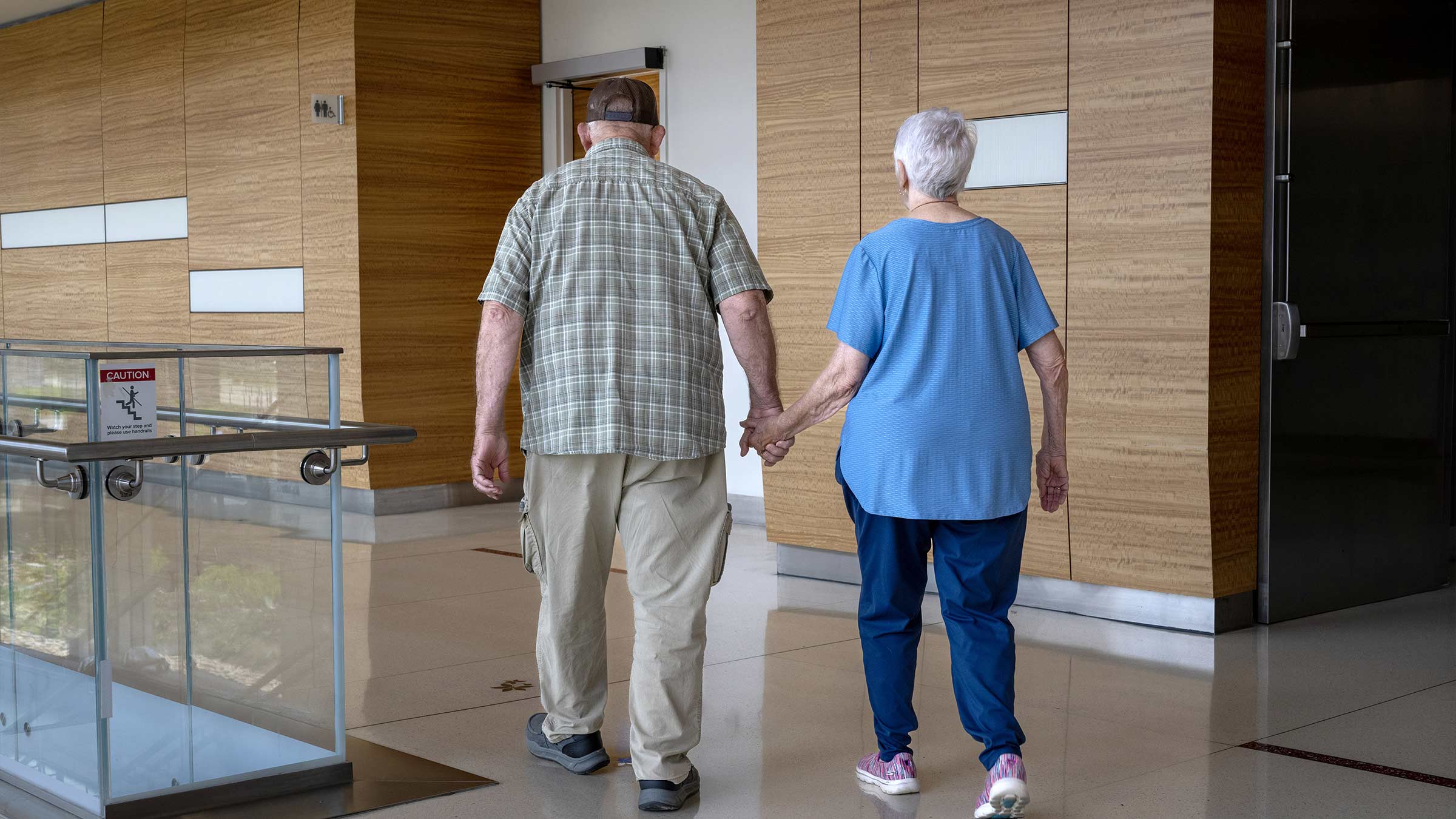 Judith Moyer holding her husband’s hand walking in the James lobby