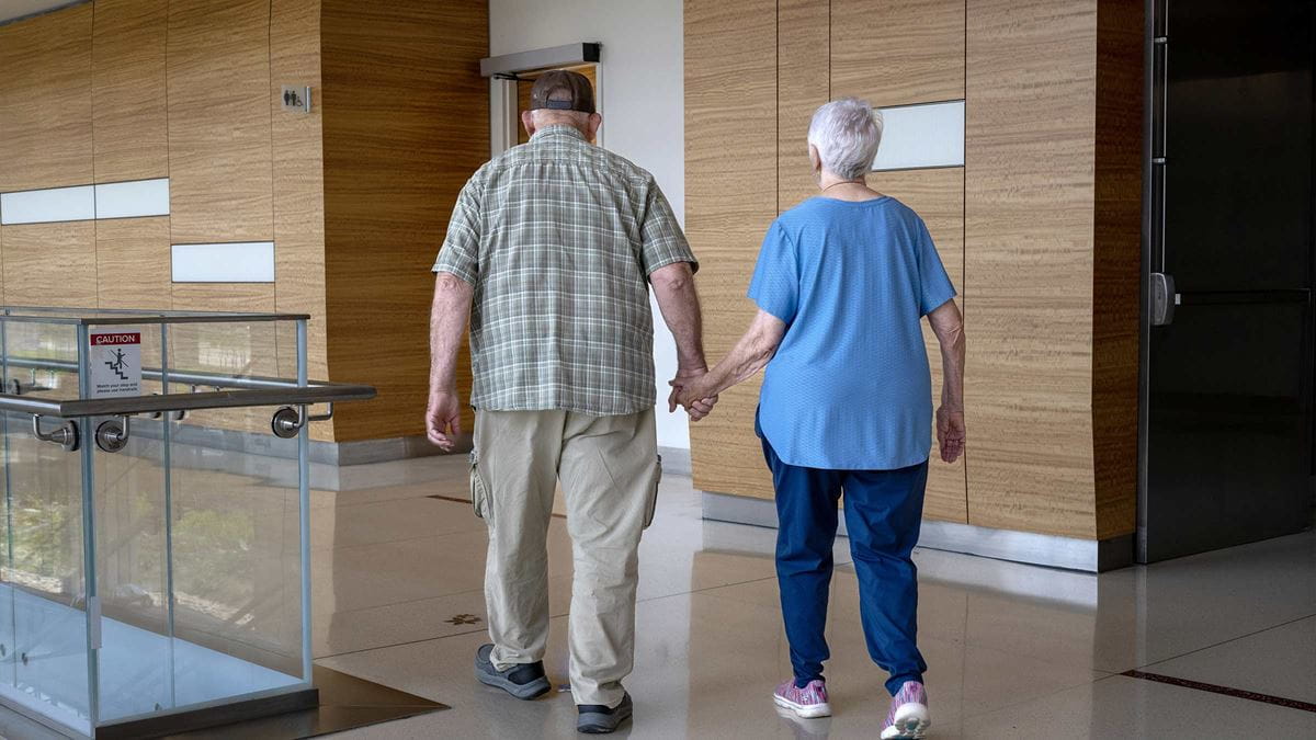 Judith Moyer holding her husband’s hand walking in the James lobby